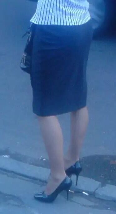 Girl in pencil skirt and heels on a bus stop