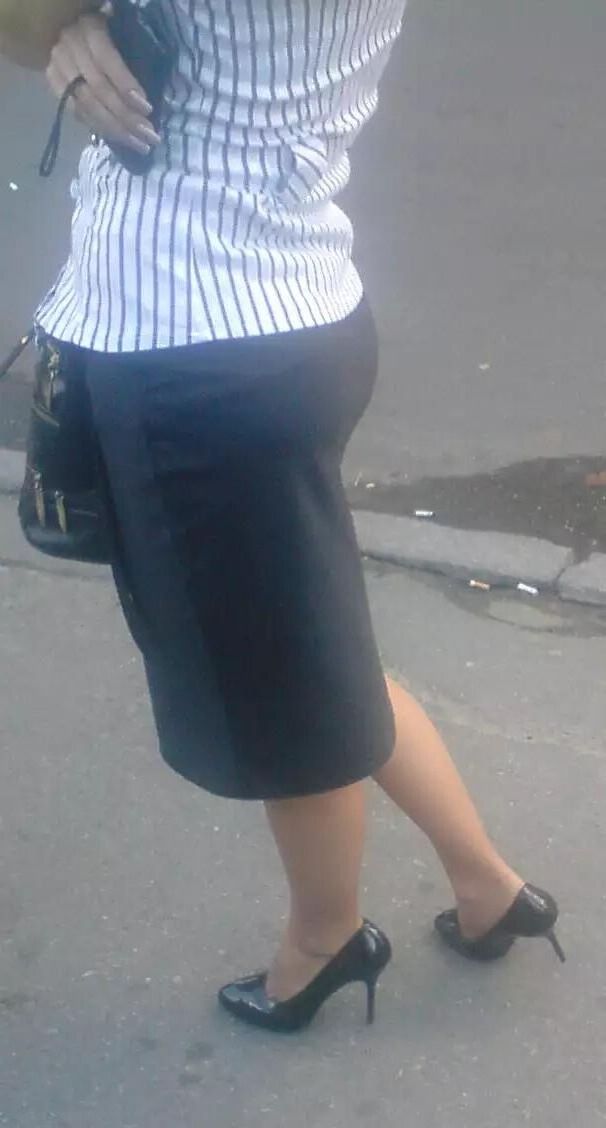 Girl in pencil skirt and heels on a bus stop