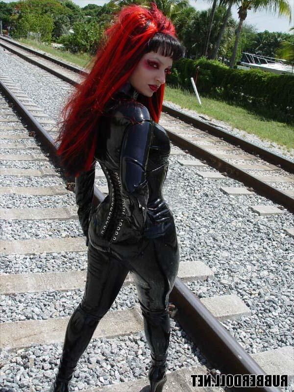 Kinky doll in black latex catsuit and public pussy spreading