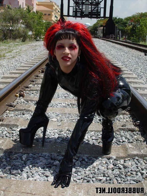 Kinky doll in black latex catsuit and public pussy spreading