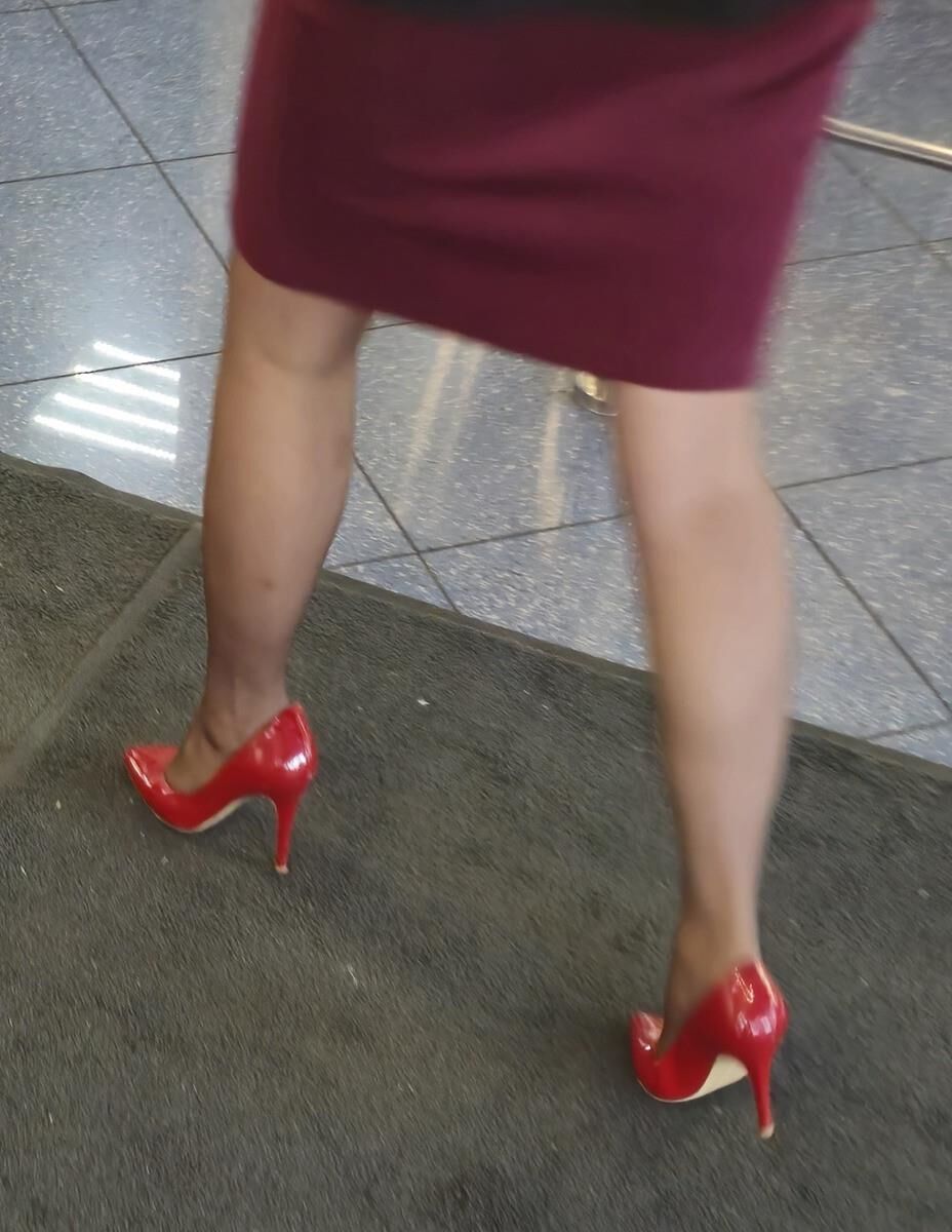 Trabalhador de cotonete em saltos vermelhos, meia -calça marrom e saia lápis