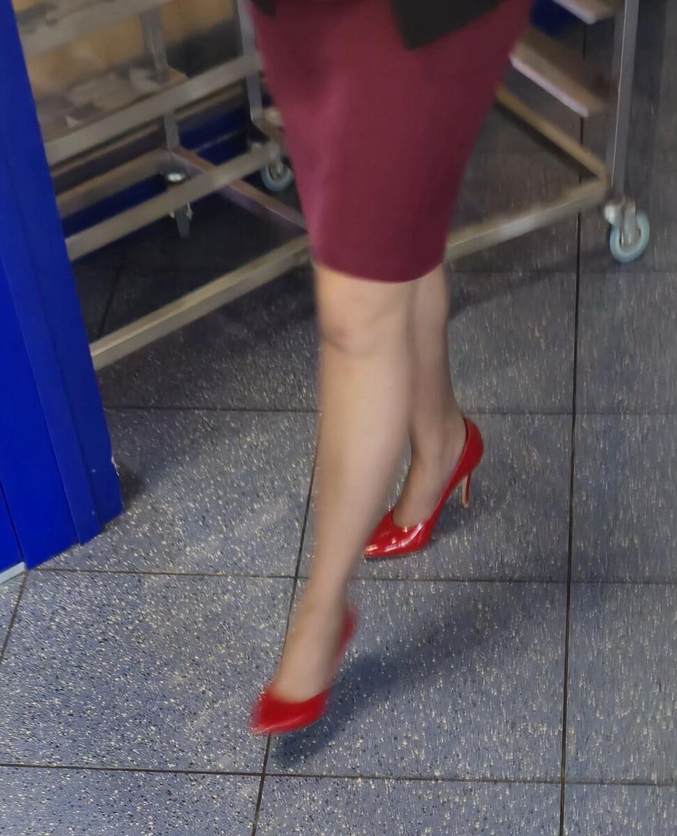 Trabalhador de cotonete em saltos vermelhos, meia -calça marrom e saia lápis