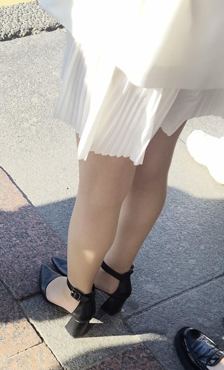 Menina de vestido branco, meias brilhantes e saltos de couro