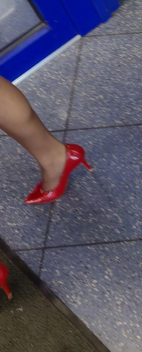 Trabalhador de cotonete em saltos vermelhos, meia -calça marrom e saia lápis