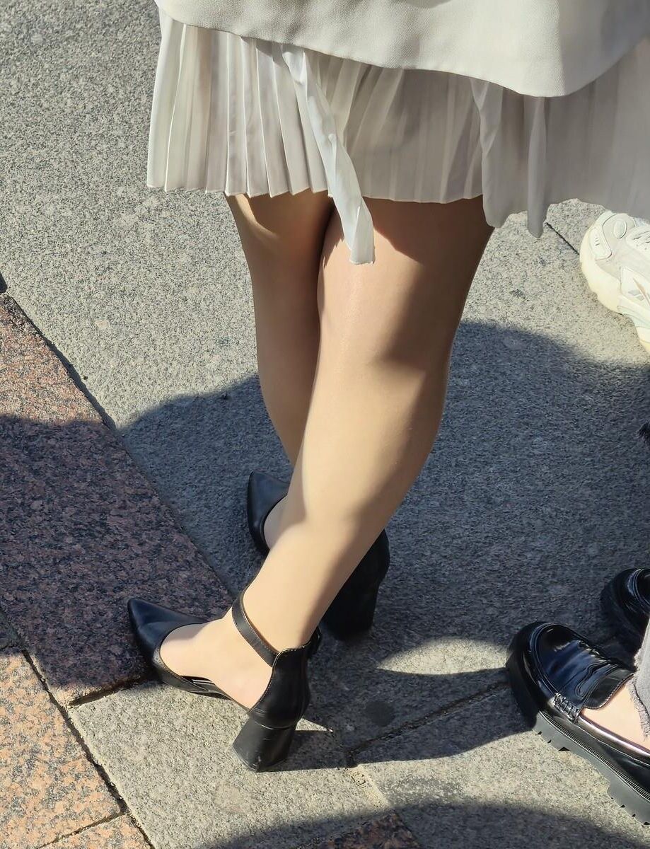 Menina de vestido branco, meias brilhantes e saltos de couro