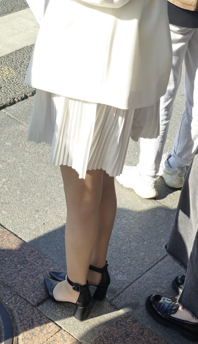 Menina de vestido branco, meias brilhantes e saltos de couro