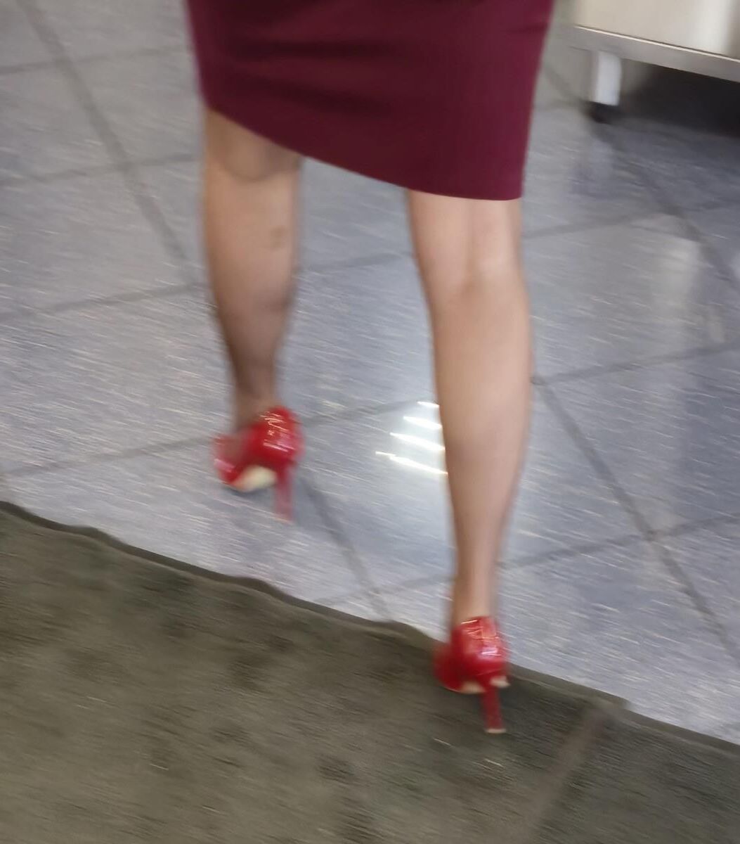 Trabalhador de cotonete em saltos vermelhos, meia -calça marrom e saia lápis