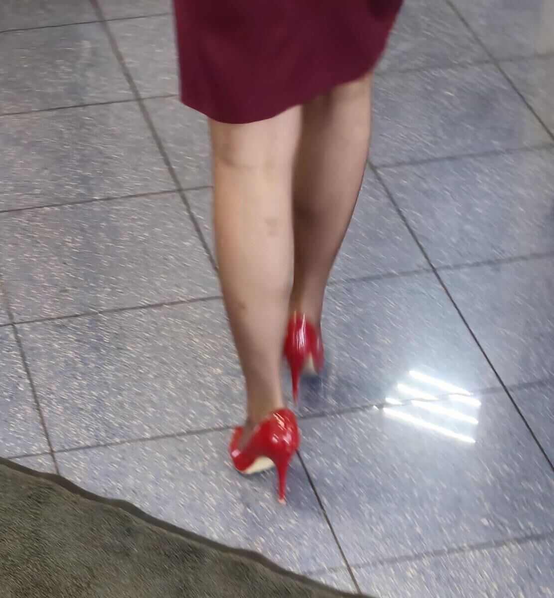 Trabalhador de cotonete em saltos vermelhos, meia -calça marrom e saia lápis