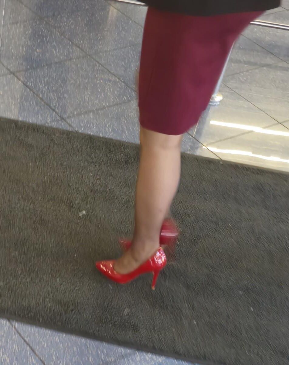 Trabalhador de cotonete em saltos vermelhos, meia -calça marrom e saia lápis