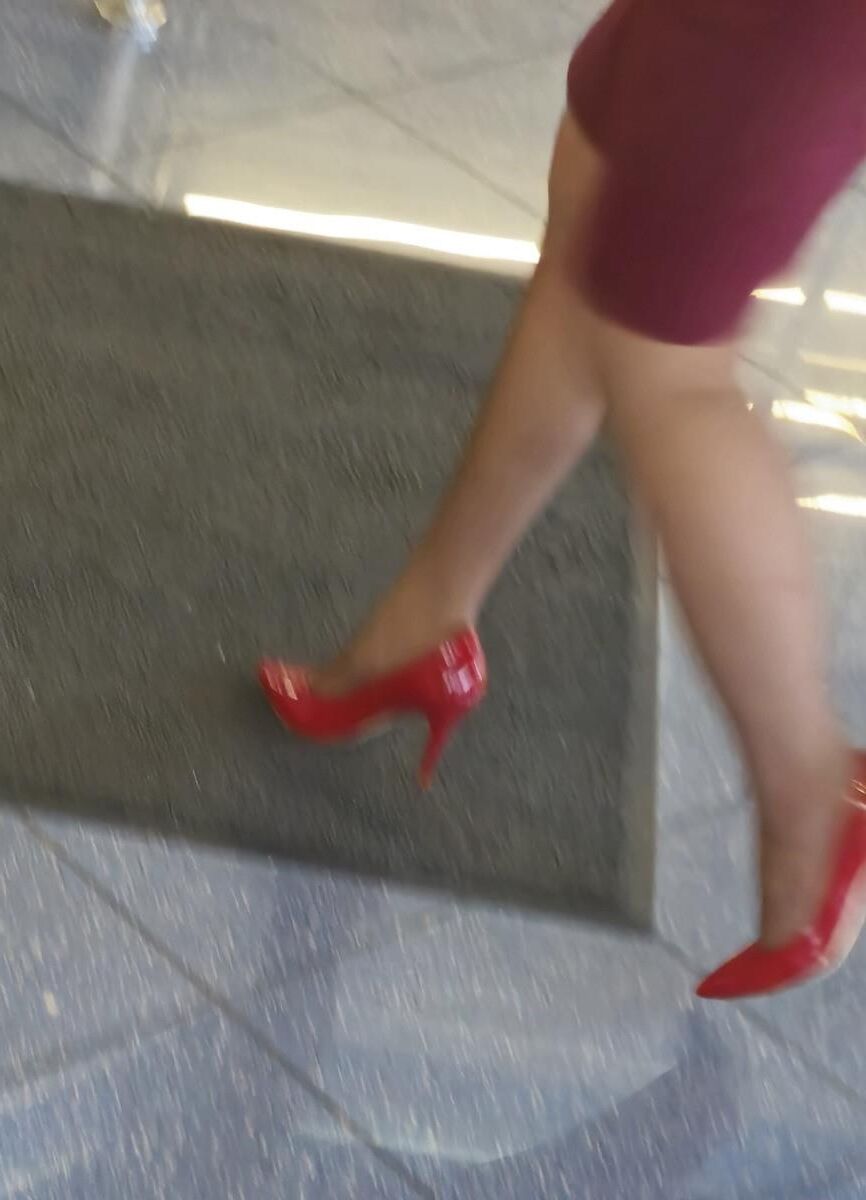 Trabalhador de cotonete em saltos vermelhos, meia -calça marrom e saia lápis