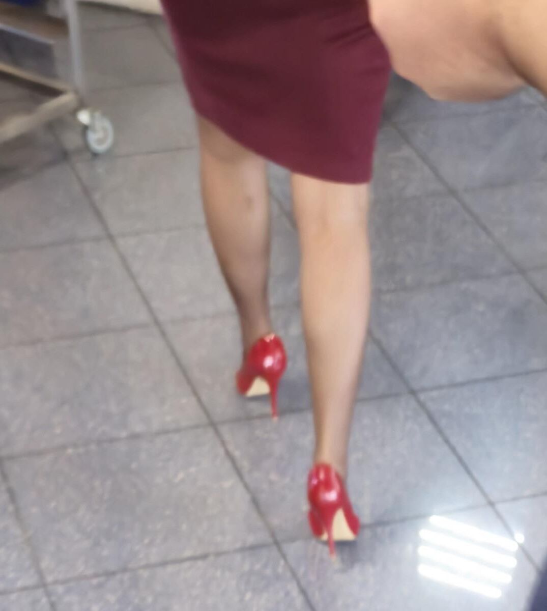 Trabalhador de cotonete em saltos vermelhos, meia -calça marrom e saia lápis