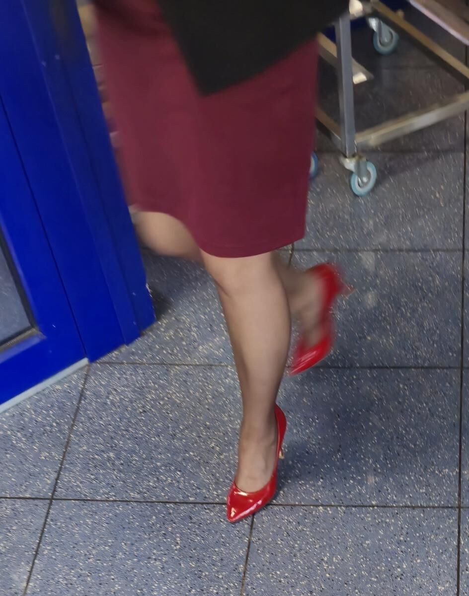 Trabalhador de cotonete em saltos vermelhos, meia -calça marrom e saia lápis