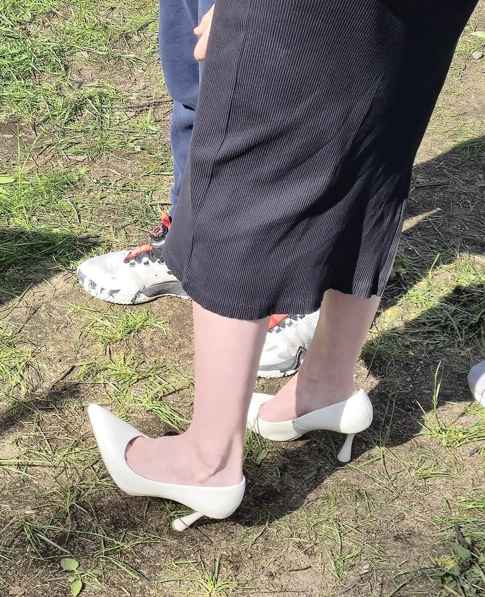 Garota de salto branco, vestido longo e jaqueta