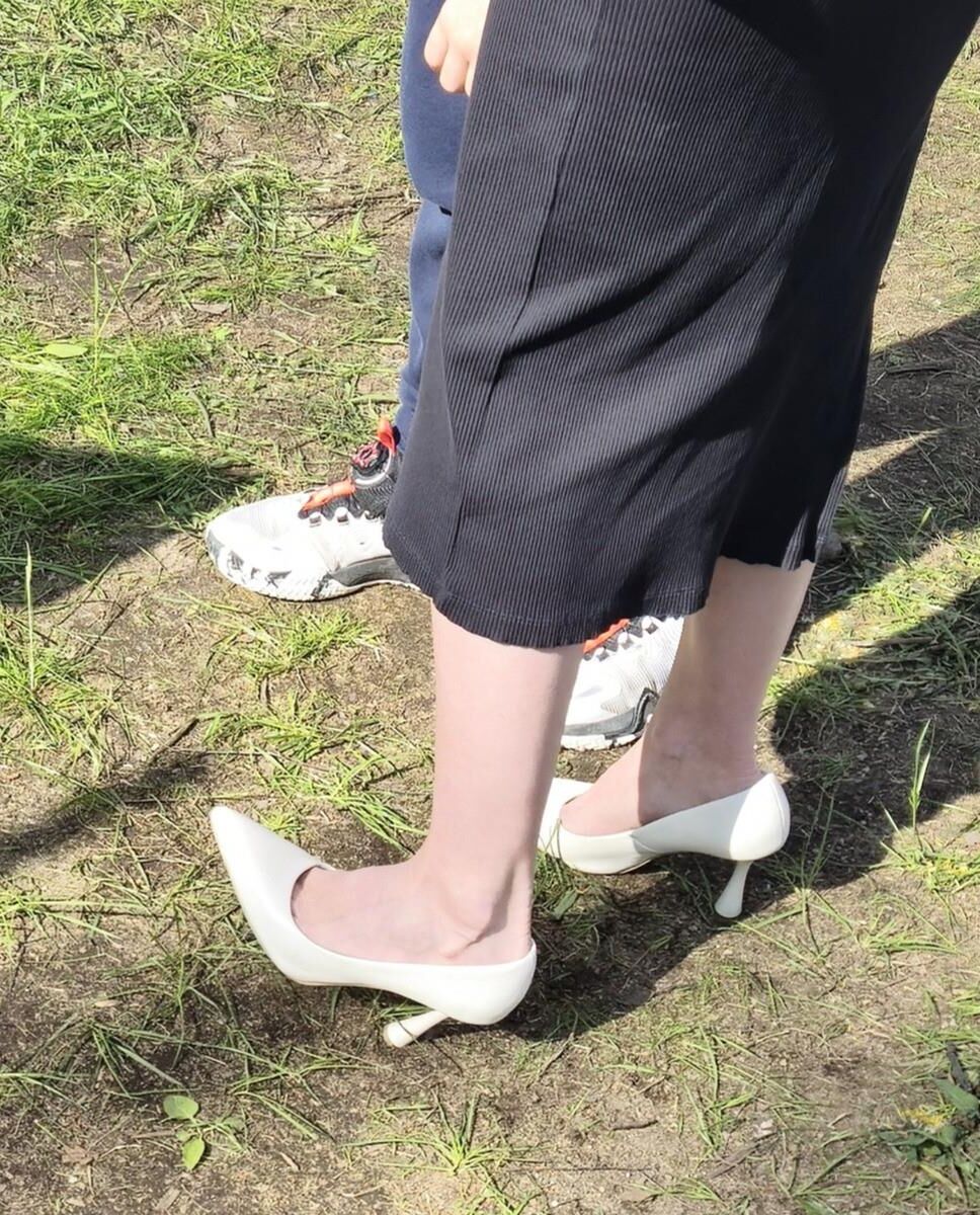 Garota de salto branco, vestido longo e jaqueta