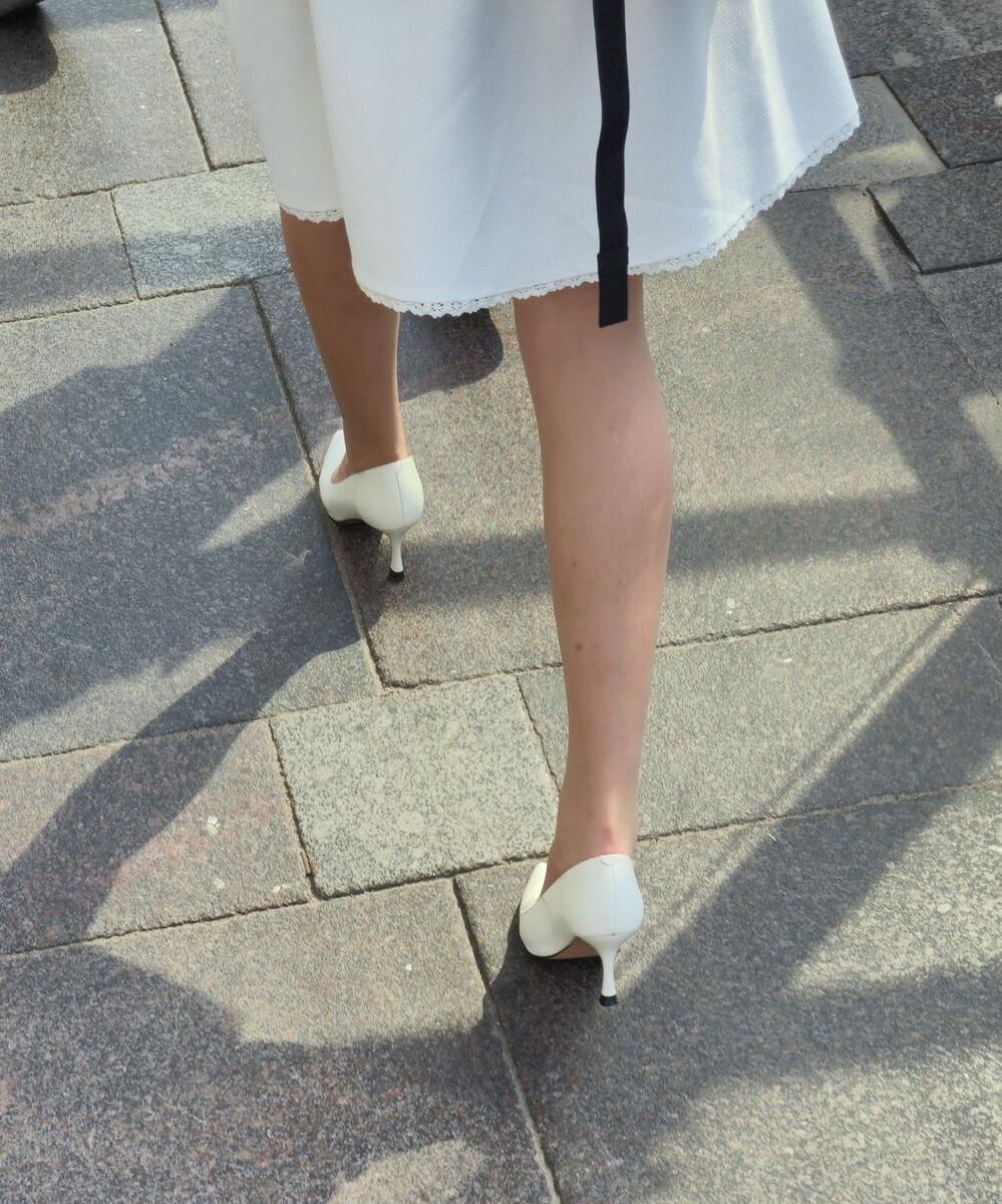 Menina de calças calças nus, saltos brancos e vestido branco
