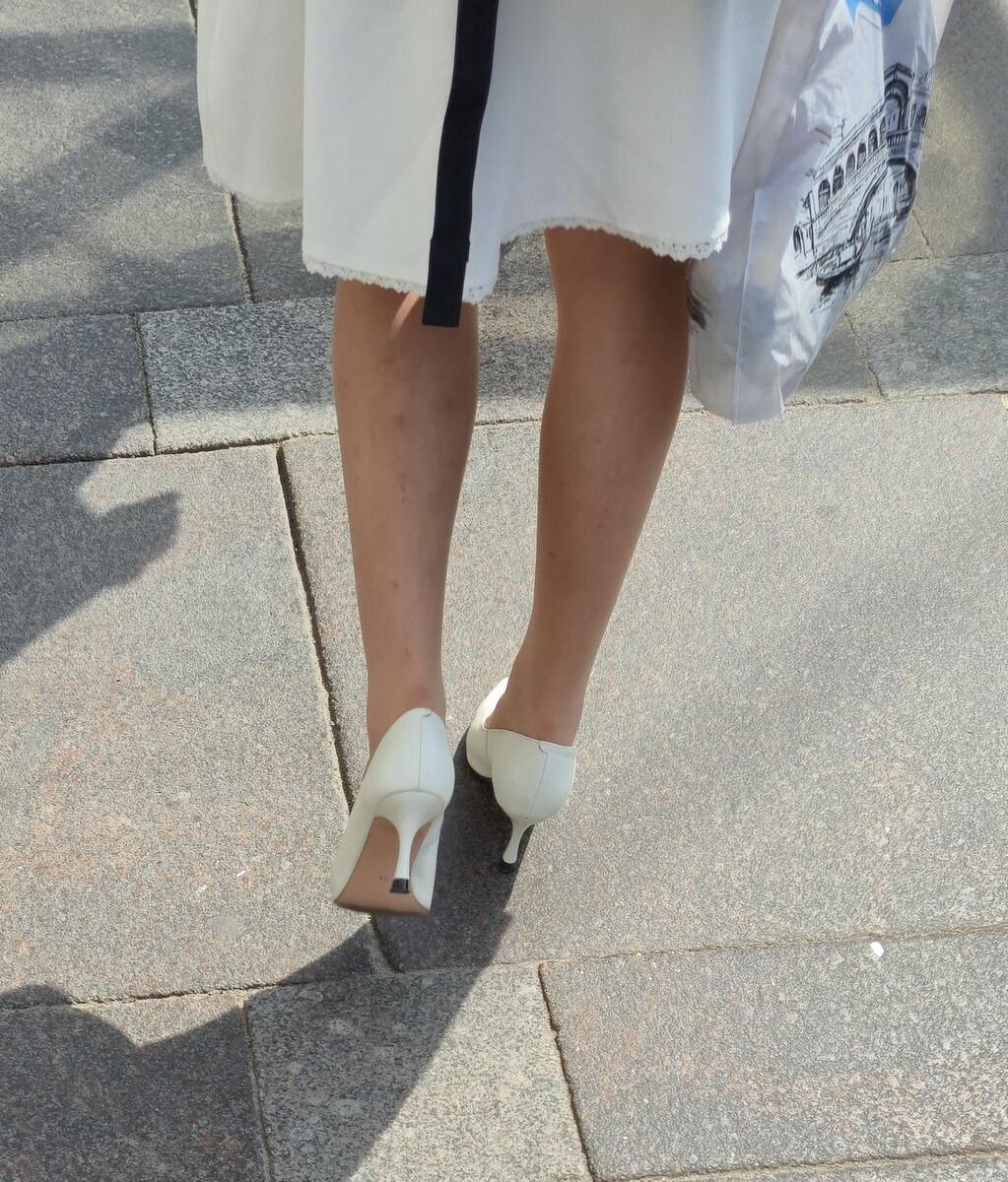 Menina de calças calças nus, saltos brancos e vestido branco