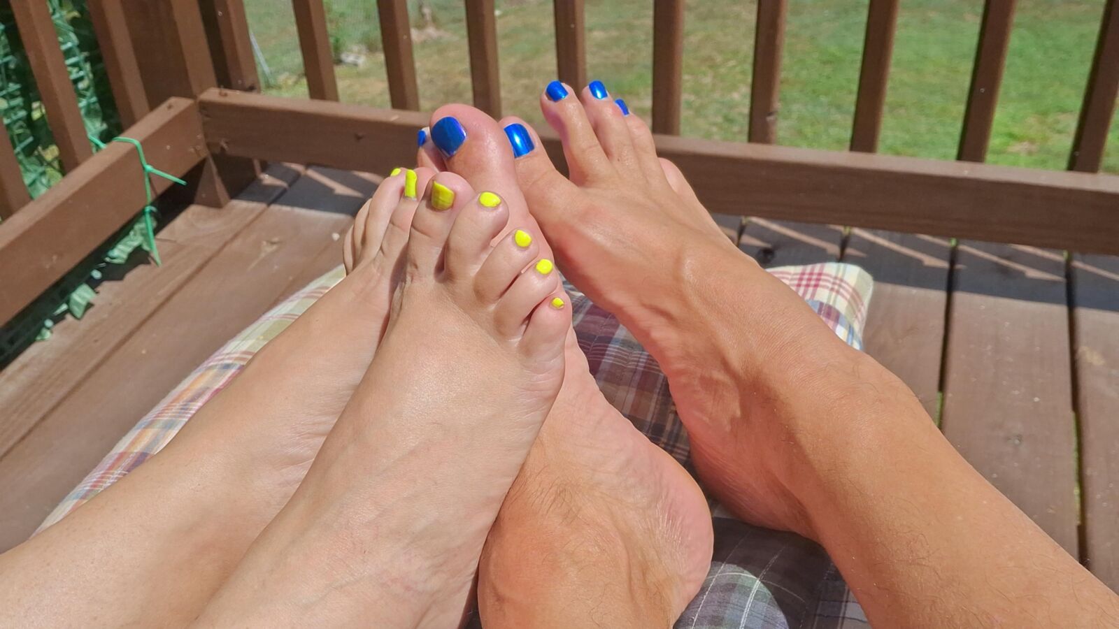 Two pairs of feet playing footsie in the sun